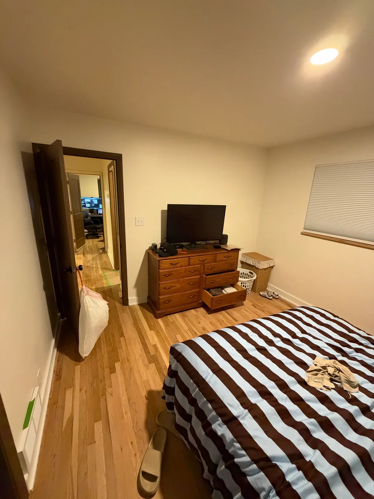 Wood dresser and television opposite the bed, next to the bedroom entrance